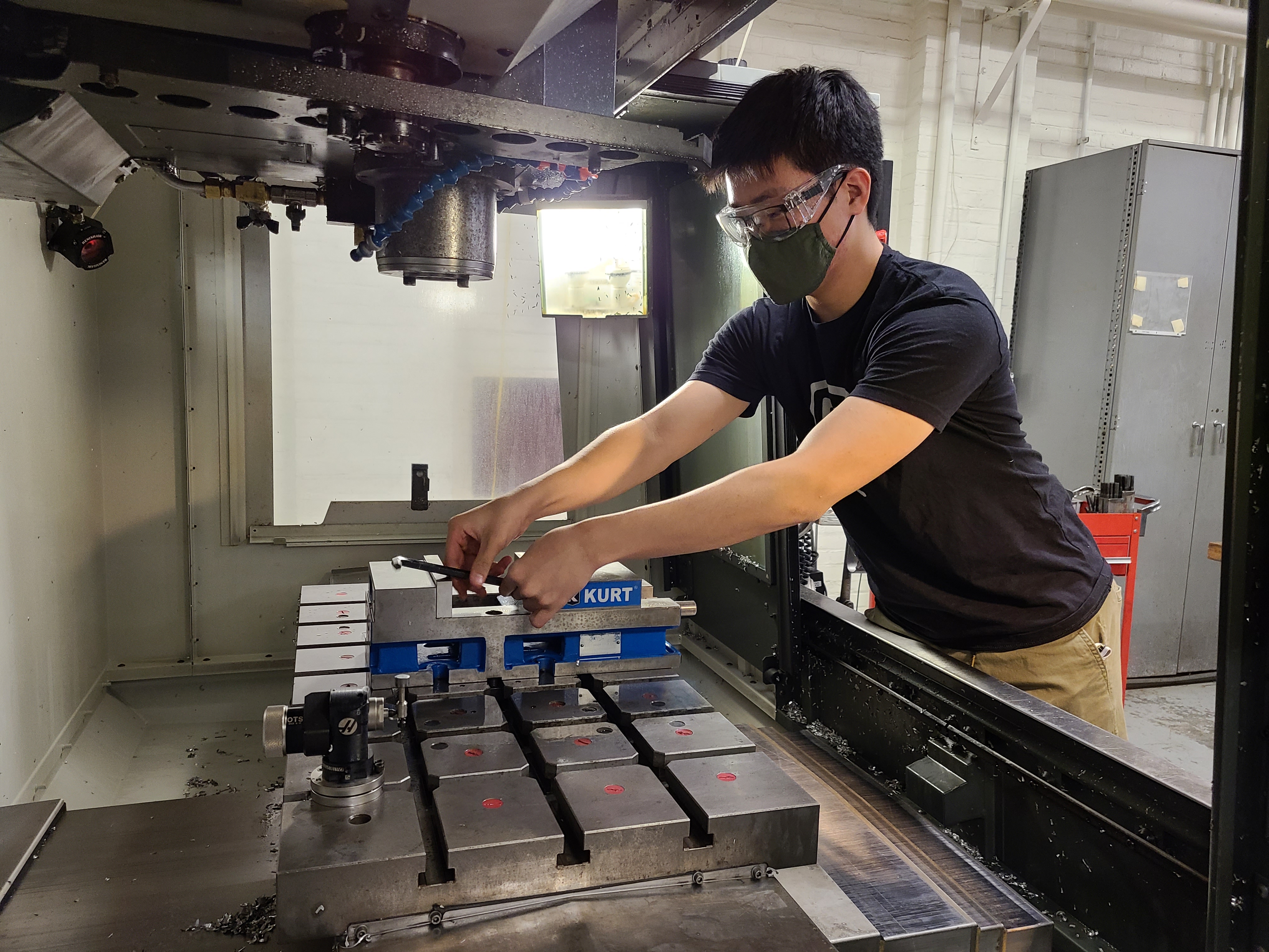 A member prepares fixtures in a CNC mill before machining components for the motor retention.